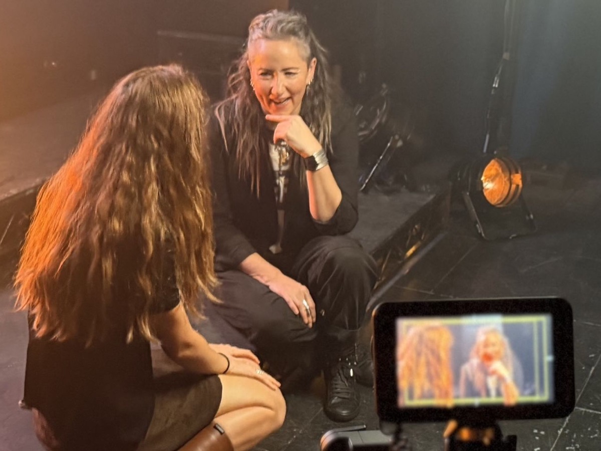 An interview being filmed on a theatre stage, the shot visible on the camera monitor